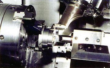 This close up of multi-axis turning center at Pacific Tool shows a part chucked in the main spindle, being bored by a tool mounted in the lower tool turret. A shoulder on the part OD is cleaned up by a tool mounted in the machine's tool spindle.